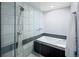 Close up of a bathroom shower and tub featuring white marble tile and black trim with white and grey tile flooring at 9383 W Colorado Ave, Lakewood, CO 80232