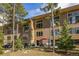 Exterior view of a multi-story building featuring patios and large windows, surrounded by lush greenery at 877 Airport Rd # 19, Breckenridge, CO 80424