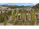 Scenic view of condo buildings nestled among lush trees with mountain backdrop and exterior patio spaces at 877 Airport Rd # 19, Breckenridge, CO 80424