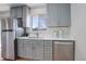 Bright kitchen featuring stainless steel appliances, gray cabinets, and quartz countertops at 230 W 78Th Pl, Denver, CO 80221