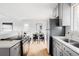 Modern kitchen with gray cabinets, white quartz countertops and stainless steel appliances open to dining area at 230 W 78Th Pl, Denver, CO 80221