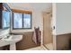 Bathroom featuring a sink with stylish fixtures, a framed window with blinds, and a shower with glass doors at 6534 Field St, Arvada, CO 80004