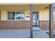 Close-up of front porch featuring brick detail, window, and steel door with screen, providing curb appeal and security at 6534 Field St, Arvada, CO 80004