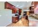 Well-lit kitchen featuring modern appliances, granite countertops, and cherry wood cabinets with hardwood floors at 6534 Field St, Arvada, CO 80004