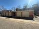 Row of garages with beige doors, one is open, in a community with brick facade and street view at 4100 Albion St # 205, Denver, CO 80216