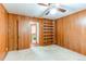 Wood paneled bedroom with ceiling fan, carpet, and built-in shelves adjacent to a bathroom at 2081 W Ridge Rd, Littleton, CO 80120