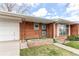 A close-up view of the home's entry way, with red brick, a green AstroTurf porch and an attached garage at 2081 W Ridge Rd, Littleton, CO 80120