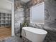 Bright bathroom showcases a modern soaking tub and stylish marble walls complemented by a large window at 62101 E 32Nd Ct, Strasburg, CO 80136