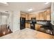 Well-equipped kitchen featuring wooden cabinets, black appliances, granite countertops, and a neutral tile floor at 1488 N Stratton Ave, Castle Rock, CO 80104