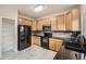 Functional kitchen with wood cabinets, black appliances, granite countertops, and neutral tile flooring with ample storage at 1488 N Stratton Ave, Castle Rock, CO 80104