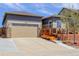 Exterior view of home with two-car garage and outdoor deck featuring wood and stone design elements at 18027 Telford Ave, Parker, CO 80134