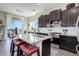 Gourmet kitchen with dark cabinetry, granite countertops, tile backsplash, and counter seating at 18027 Telford Ave, Parker, CO 80134