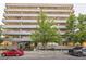 Multi-story apartment building with a lush green tree in front and two cars parked on the street at 1441 N Humboldt St # 504, Denver, CO 80218