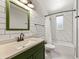 An updated bathroom with white subway tile, a green vanity, and a tub/shower combination at 971 Ursula St, Aurora, CO 80011