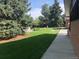 Landscaped backyard with spacious lawn, trees, and a walkway at 5030 Aspen Dr, Littleton, CO 80123