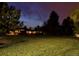 Night view of a ranch-style home with a large lawn at 5030 Aspen Dr, Littleton, CO 80123