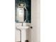 Stylish powder room with geometric wallpaper, gold fixtures, a pedestal sink, and white door at 10106 E 59Th Pl, Denver, CO 80238