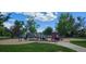 Colorful playground equipment on a sandy surface, surrounded by green grass and mature trees at 1089 S Osceola St, Denver, CO 80219