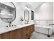 Spa-like bathroom featuring a double vanity, oval mirrors, and a modern soaking tub at 2376 S Bannock St, Denver, CO 80223