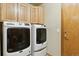 This is a well-lit laundry room with front load washer and dryer and wood cabinets for storage at 4143 Eagle Ridge Way, Castle Rock, CO 80104