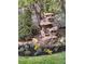 Outdoor space with a small decorative stone waterfall surrounded by vibrant flower gardens and lush greenery at 4143 Eagle Ridge Way, Castle Rock, CO 80104