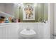 Stylish powder room features a pedestal sink, decorative mirror, and wainscoting, adding charm and character to the home at 1343 Valentia St, Denver, CO 80220