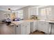 Open-concept kitchen featuring a breakfast bar, white cabinetry, and stainless steel appliances, seamlessly connecting to the living area at 1343 Valentia St, Denver, CO 80220