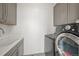 Well-equipped laundry room with modern washer and dryer, ample cabinet storage, and a utility sink at 14102 Night Owl Ln, Parker, CO 80134