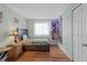 Bright bedroom features wood floors, a bed with a floral pattern, and a window with white curtains at 18982 E 46Th Ave, Denver, CO 80249