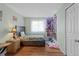 Bright bedroom features wood floors, a bed with a floral pattern, and a window with white curtains at 18982 E 46Th Ave, Denver, CO 80249
