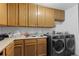 Laundry room with modern washer/dryer units and oak cabinets at 18982 E 46Th Ave, Denver, CO 80249