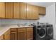 Laundry room with modern washer/dryer units and oak cabinets at 18982 E 46Th Ave, Denver, CO 80249