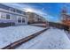 View of backyard with snow, retaining wall, and deck at 5780 Raleigh Cir, Castle Rock, CO 80104