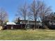 Two-story home with a covered back deck and large mature trees, looking out over the backyard at 7055 S Costilla St, Littleton, CO 80120