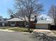 Street view of brick ranch-style home featuring mature trees, an attached garage, and landscaped front yard at 7055 S Costilla St, Littleton, CO 80120