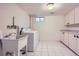 Well-lit laundry room with white cabinets, white tiled floors, and washer/dryer for convenient chores at 7055 S Costilla St, Littleton, CO 80120