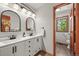 Bright bathroom featuring double sink vanity, modern mirrors, and views to the commode at 6862 Independence Ct, Arvada, CO 80004