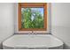 Large soaking tub under a window overlooking trees and landscaping at 6862 Independence Ct, Arvada, CO 80004