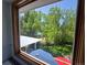 View from the window shows a backyard with mature trees, landscaping, and a patio with an umbrella at 6862 Independence Ct, Arvada, CO 80004