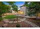 Landscaped backyard with patio, stone pathway, garden beds and manicured lawn at 7114 S Acoma Way, Littleton, CO 80120