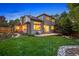 Beautifully landscaped backyard with green grass, patio, mature trees, and a charming outdoor seating area at 7114 S Acoma Way, Littleton, CO 80120
