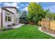 Landscaped backyard with green grass, a stone patio, a wooden fence, and mature trees at 7114 S Acoma Way, Littleton, CO 80120