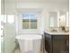 Bright bathroom featuring freestanding tub, glass shower enclosure, dual sink vanity, and patterned tile flooring at 7114 S Acoma Way, Littleton, CO 80120