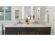 Bright bathroom featuring double sink vanity, lighted mirror, and modern fixtures, with shelving in the background at 7114 S Acoma Way, Littleton, CO 80120