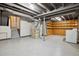 Unfinished basement with painted floor, utility area, and shelving at 8174 Dudley Cir, Arvada, CO 80005