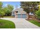 Charming blue two-story home with brick accents, a well-manicured lawn, and a long concrete driveway at 8174 Dudley Cir, Arvada, CO 80005