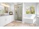 Bright bathroom featuring soaking tub, stone shower, and double vanity at 134 S Pontiac St, Denver, CO 80230