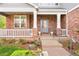 Inviting front porch with brick pillars, a decorative railing, manicured landscaping, and a visible house number at 134 S Pontiac St, Denver, CO 80230