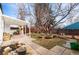 Spacious backyard with a large tree, patio, chicken coop, and beautiful landscaping at 3256 S Glencoe St, Denver, CO 80222