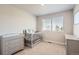 Bedroom with gray crib, dresser, and changing table, complemented by a bright window at 1353 Reynolds St # 2B, Fort Lupton, CO 80621
